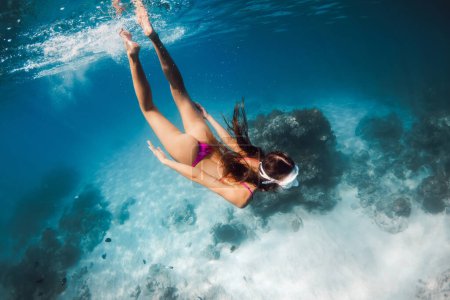 Téléchargez les photos : Femme avec corps parfait plongée en apnée dans la mer bleue. Nager sous l'eau dans l'océan sur Oahu - en image libre de droit
