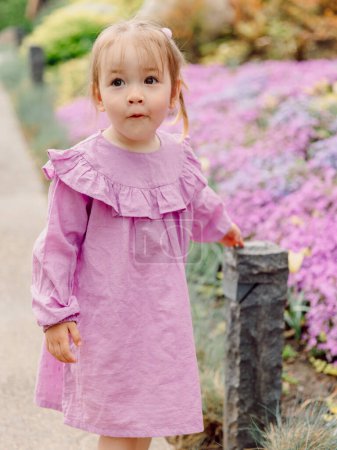 Portrait of cute child girl in blooming summer garden or park.
