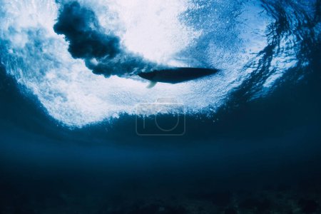 Téléchargez les photos : Surfeur sur planche de surf dans la vue sous-marine de l'océan. Vague d'écrasement et planche de surf en eau transparente - en image libre de droit