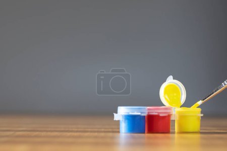 Foto de Artist paint brush with colorful paint on wooden table with gray background, copy space blue, red and yellow close up - Imagen libre de derechos
