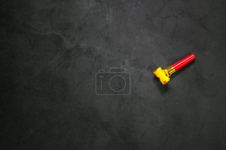Photo for Birthday party blowouts whistles Rolled festive noisemaker or party whistle on concrete dark background, blowing in whistle top view in and out loop 4k Happy Birthday copy space - Royalty Free Image