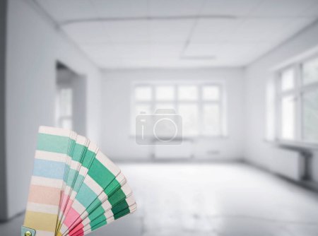 Farbpalette und Pinsel Auswahl einer Wandfarbe in einem neuen Zuhause. Ein Mann und eine Frau zogen in ein neues Haus. Selektiver Fokus verschwommener Raumhintergrund, muss renoviert werden