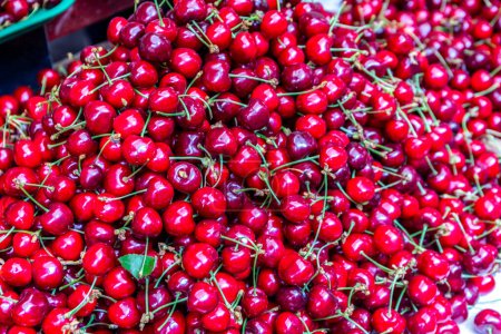Téléchargez les photos : Plenty of red cherries with stems, harvested, on market stall in Kutaisi Central Market (Green Bazaar,  Mtsvane Bazari). - en image libre de droit