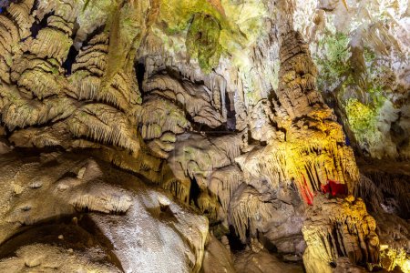 Téléchargez les photos : Pierre d'écoulement (cascades de pétrification, draperies) dans le monument naturel de la grotte Prometheus, plafond avec stalactites et stalagmites, formations rocheuses illuminées colorées. - en image libre de droit