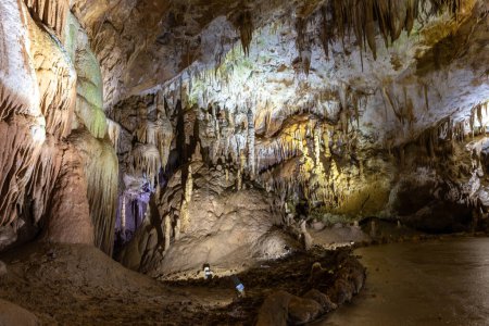 Téléchargez les photos : Monument naturel de la grotte Prometheus - la plus grande grotte de Géorgie avec des rideaux de pierre suspendus, des stalactites et des stalagmites, des formations rocheuses illuminées colorées et un sentier touristique. - en image libre de droit