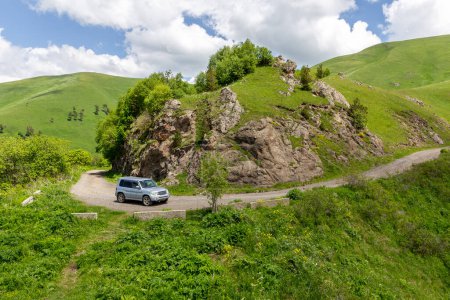Foto de Coche 4x4 conduciendo por la carretera de grava M-20 sinuosa hacia el paso Tskhratskaro, Georgia con montañas de Trialeti (Cáucaso) y pastizales verdes alrededor. - Imagen libre de derechos