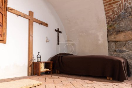 Photo for Avila, Spain, 08.10.21. Ascetic monastic cell in the Museum and house of Santa Teresa of Avila, inside view of Saint's room with simple bed and wooden cross. - Royalty Free Image