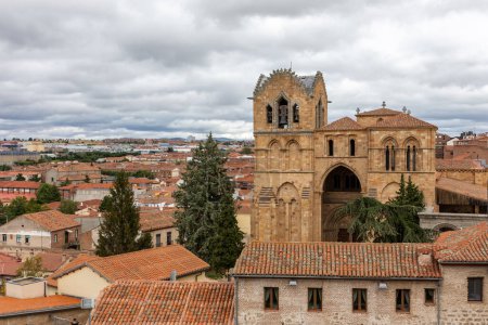 Foto de Paisaje urbano de Ávila (España) con Basílica de San Vicente iglesia de arquitectura románica y tejados de azulejos de edificios medievales antiguos, vista desde el Muro de Ávila. - Imagen libre de derechos