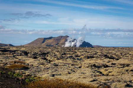 Paysage volcanique de la péninsule de Reykjanes avec champs de lave et vapeur de gaz de la centrale géothermique Svartsengi et de la lagune bleue, vue de la route 43, Islande.