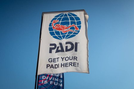 Photo for Fujairah, UAE, 26.10.20. PADI (The Professional Association of Diving Instructors), diving training organization flag with logo (diver with a torch in a globe) in front of the dive shop on the beach. - Royalty Free Image