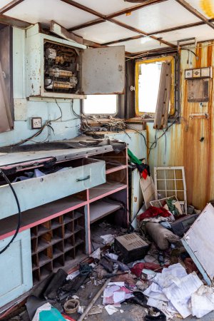 Wheelhouse of a demolished cargo ship wreck after marine disaster, inside view of desk with communication devices and equipment, Al Hamriyah beach in Umm Al Quwain, United Arab Emirates.