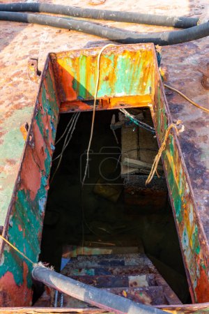 Damaged gangway with ladder leading to lower deck of a crashed cargo ship, flooded with water, wreck beached ashore on the Al Hamriyah beach in Umm Al Quwain, United Arab Emirates.