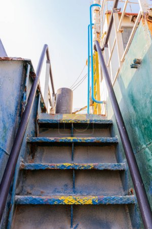 Old rusty vertical staircase with paint peeling off, leading to the upper deck of the wreck of cargo ship beached on the Al Hamriyah beach in Umm Al Quwain, United Arab Emirates.