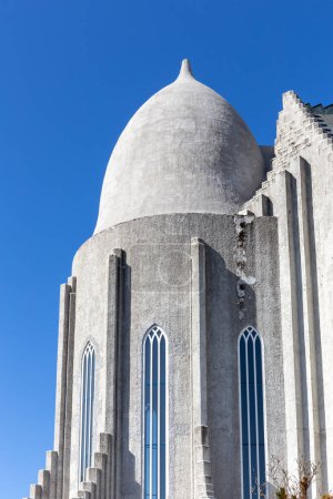 Edificio santuario de la iglesia Hallgrimskirkja con cúpula cilíndrica evocando cascos de guerra vikingos, cielo azul cristal, Reikiavik, Islandia.