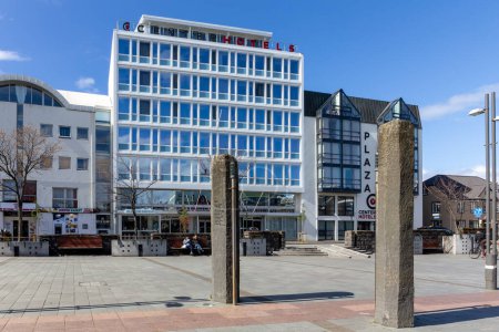 Téléchargez les photos : Reykjavik, Islande, 14.05.22. Piliers de siège d'Ingolfur Arnarson, piliers de basalte sur la place Ingolfur commémorant l'histoire de la colonisation à Reykjavik avec le bâtiment Center Hotels Plaza. - en image libre de droit