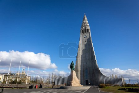 Photo for Reykjavik, Iceland, 14.05.22. Hallgrimskirkja modernist church building with Leif Erikson statue in front on Skolavorduholt hill, blue sky. - Royalty Free Image