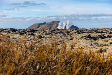 Paysage volcanique de la péninsule de Reykjanes avec champs de lave et vapeur de gaz de la centrale géothermique Svartsengi et de la lagune bleue, vue de la route 43, Islande.