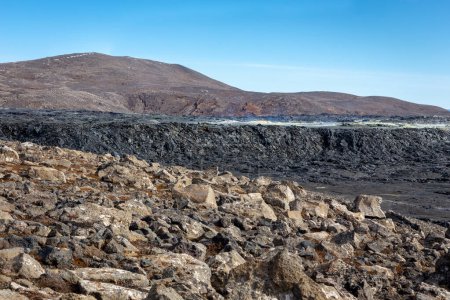 Paisaje del campo de lava del volcán Fagradalsfjall con lava basáltica congelada creada después de la erupción, respiraderos humeantes y nuevo cono del cráter, Islandia.