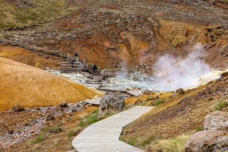 Téléchargez les photos : Krysuvik, Islande, 14.05.22. Paysage de Seltun Geothermal Area à Krysuvik avec des sources chaudes mijotantes, des couleurs jaunes et orange des collines de soufre et des promenades touristiques. - en image libre de droit