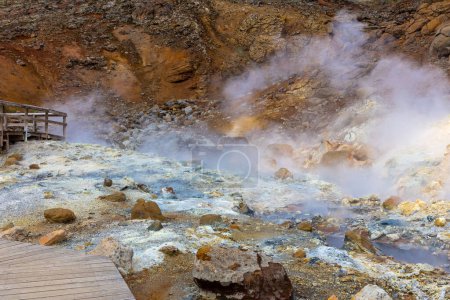 Landschaft des geothermischen Gebiets Seltun in Krysuvik mit brodelnden heißen Quellen, gelben und orangen Schwefelfarben und Touristenpromenaden, Island.