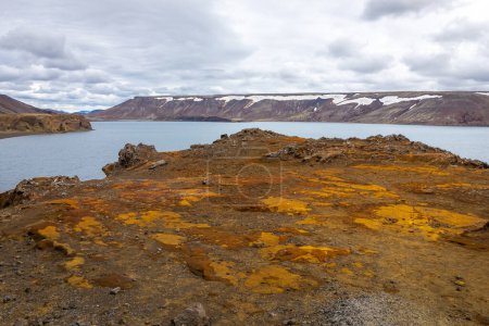 Paisaje de la península de Reykjanes, con lago Kleifarvatn, campos de lava estériles cubiertos de musgo, suelo de azufre naranja y acantilados nevados en el fondo.