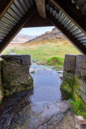 Hrunalaug Hot Spring, Blick auf die natürlichen Mineralbäder und Becken aus dem Inneren des alten Holzschuppens, der als Umkleidekabine genutzt wird, Island.