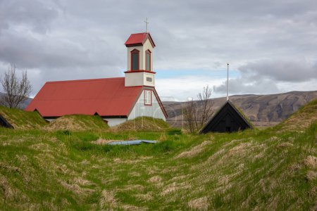 Foto de Granja Keldur en Islandia con Keldnakirkja iglesia de 1875 y fila de antiguas casas de césped cubierto de hierba y musgo. - Imagen libre de derechos
