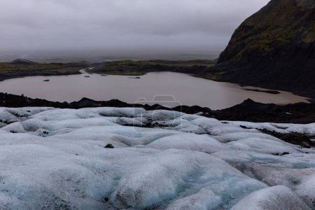 Retreating Skaftafell Glacier in Vatnajokull National Park, Iceland. Blue glacier ice with cracks and crevasses, with the view of the glacier lagoon below.