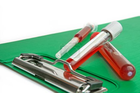 Foto de Sample blood in tube for test and New patient information sheet in file with syringe on white background. - Imagen libre de derechos