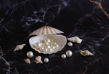 Photo for Several white pearls in a shell against a background of black marble - Royalty Free Image