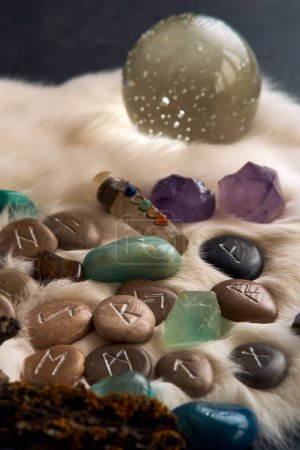 runes de pierre faites à la main, boule de cristal et pierres précieuses sur fourrure blanche pour prédire l'avenir