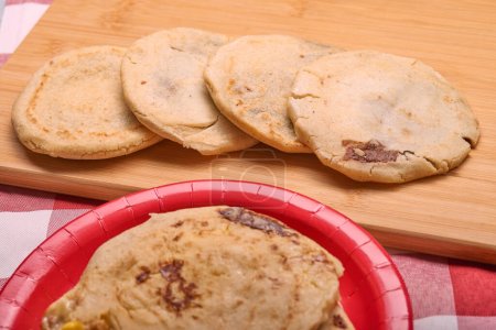 Photo for Savor the rich flavors of El Salvador with pupusas, a traditional Central American dish, served with curtido and savory sauce on a rustic wooden board - Royalty Free Image
