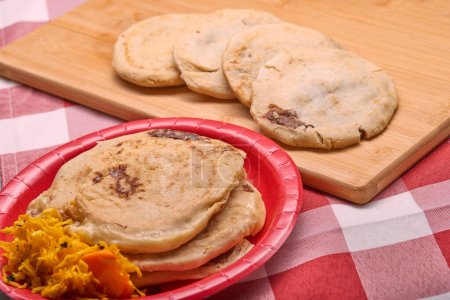 Photo for Savor the rich flavors of El Salvador with pupusas, a traditional Central American dish, served with curtido and savory sauce on a rustic wooden board - Royalty Free Image