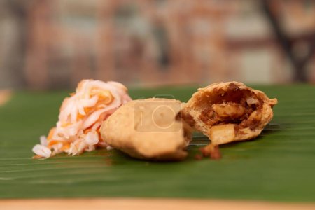 Photo for A tempting photo of a savory Salvadoran pastelito, showcasing its authentic taste and culinary artistry, set in a restaurant-style ambiance on a wooden surface accentuated by a leaf - Royalty Free Image