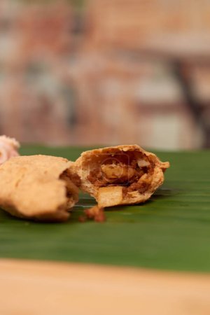 Téléchargez les photos : Une photo tentante d'un pastelito salé salvadorien, mettant en valeur son goût authentique et son art culinaire, situé dans une ambiance de restaurant sur une surface en bois accentuée par une feuille - en image libre de droit