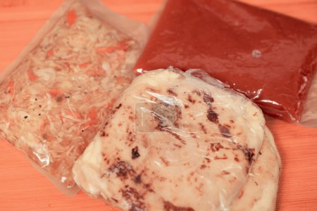 pupusas ake-away enveloppés dans du papier et du plastique, servis avec du curtido et de la sauce, prêts à déguster n'importe où.