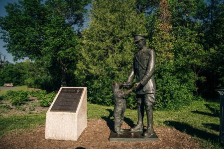 Foto de Winnipeg, Manitoba, Canadá - 2022: Estatua del Teniente Harry Colebourn y Winnie the bear, inspiración para el Winnie the Pooh. Estatua de Winnie el oso en el zoológico de Assiniboine Park - Imagen libre de derechos