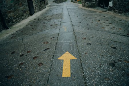 Yellow arrow painted in a road. Directional sign for pilgrims in Saint james way. Camino de Santiago, Galicia, Spain. High quality photo