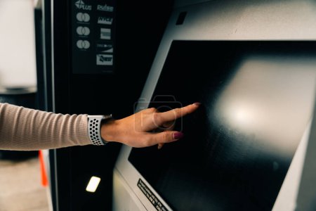 Mädchen klickt auf den Bildschirm am Geldautomaten. Hochwertiges Foto
