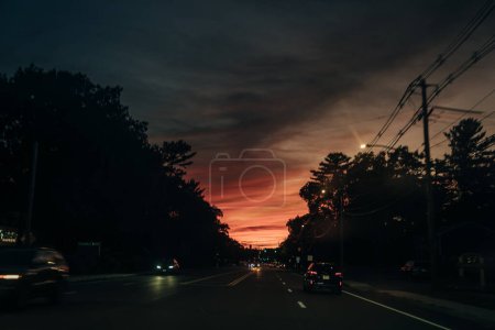 Silhouette roter Ampeln gegen kleine Wolken im Sonnenuntergang. Hochwertiges Foto