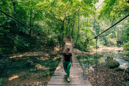 Ein Mädchen spaziert auf einer Hängebrücke in einem tropischen Wald. Hochwertiges Foto