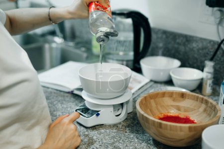 Téléchargez les photos : Femme pesant la farine sur une balance de cuisine pour faire du gâteau à la maison. Photo de haute qualité - en image libre de droit