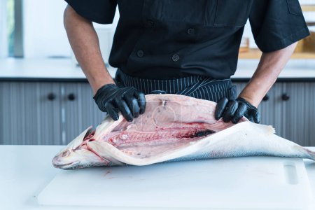 Téléchargez les photos : Chef japonais nettoyant le saumon. Un travailleur coupant du saumon sur une planche. - en image libre de droit