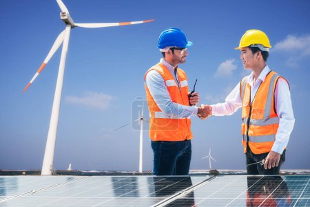 Foto de Solar and wind farm renewable energy. Engineer and Young technician shake hands around wind solar station. - Imagen libre de derechos