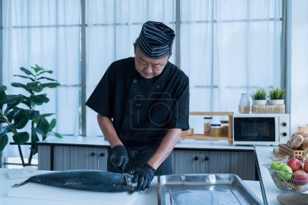 Téléchargez les photos : Chef japonais nettoyant le saumon. Un travailleur coupant du saumon sur une planche. - en image libre de droit