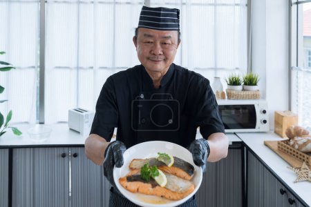 Téléchargez les photos : Poisson de mer frit. Chef japonais avec viande de saumon. Steaks de saumon servis avec des quartiers de citron. - en image libre de droit