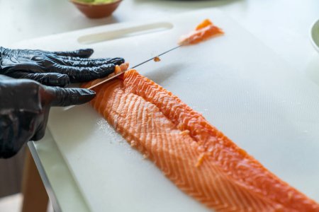 Téléchargez les photos : Chef japonais préparant un filet de saumon frais dans la cuisine. Gros plan main du chef avec du saumon sashimi. - en image libre de droit