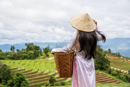 Photo for Young Vietnamese woman looking at beautiful rice terraces. Countryside culture and farm wearing wear at mountains. - Royalty Free Image