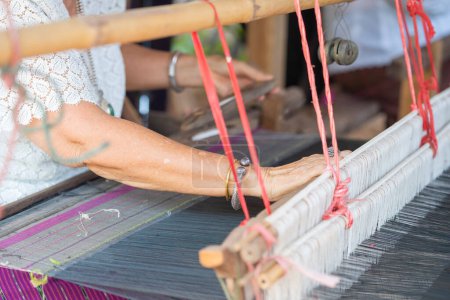 Photo for Traditional Isan Thai silk weaving. Older women hand weaving silk in traditional way at manual loom. - Royalty Free Image