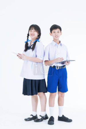 Téléchargez les photos : Je retourne à l'école. Des étudiants thaïlandais. Deux écoliers souriants asiatiques avec de la papeterie colorée. Étudiant avec tablette. - en image libre de droit